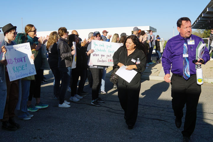 Board Trustee Ruth Martinez and Assistant Superintendent of Human Resources Shawn Premo are cheered on as they walk to the boardroom.