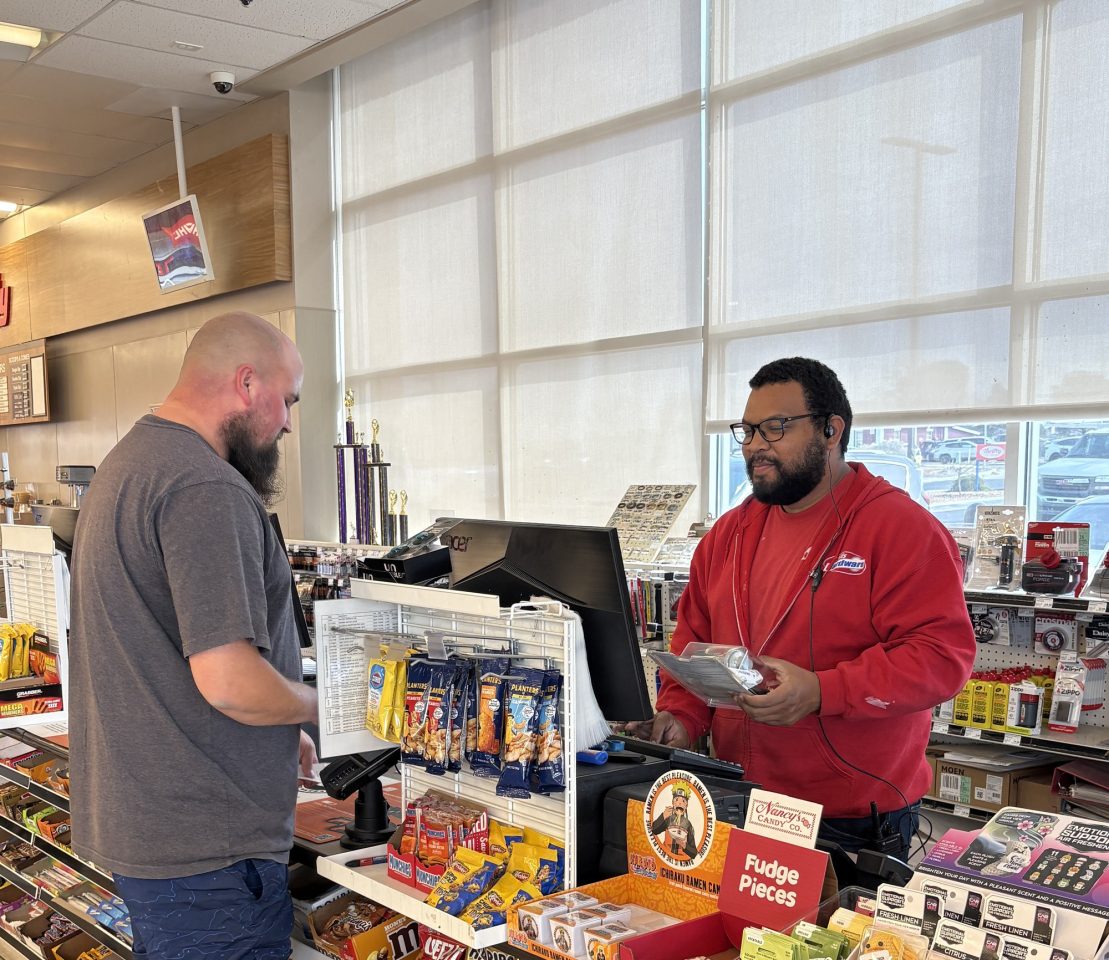 Chris, an employee of Mills Hardware, happily helps a customer check his items.